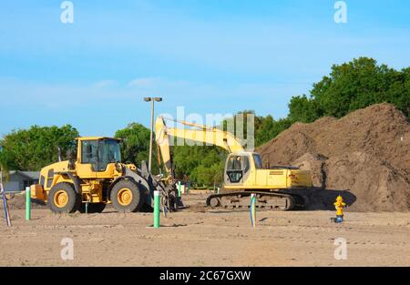 Bagger und Bulldozer auf einer Baustelle mit einem großen Haufen Schmutz Vorbereitung für Haus oder Geschäftsgebäude; bunte Bäume und blauen Himmel in Bac Stockfoto