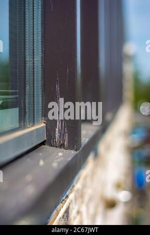 Beschädigte moderne Fensterrahmen in schlechtem Zustand, die renoviert und neu lackiert werden müssen. Vertikales Foto. Stockfoto
