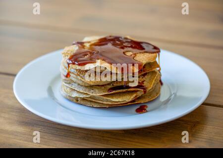 Stapel von hausgemachten einfachen amerikanischen Stil Pfannkuchen mit goldenem Sirup über sie auf Holztisch gegossen Stockfoto