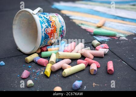Große farbige Straßenkreide. Plastikeimer mit Gehwegkreide mit kreativer Zeichnung des Kindes im Hintergrund Stockfoto