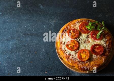 Käse und Tomatenpizza auf einem Hintergrund mit selektivem Fokus. Pizza ist ein Junk-Food, ungesund, aber eine Delikatesse für den Geschmack Knospen. Stockfoto