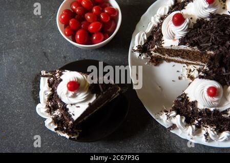 Ein Stück Schwarzwälder Kuchen und Kirschen auf einem Hintergrund mit Verwendung von selektivem Fokus Stockfoto