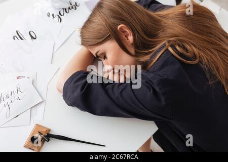Portrait der schönen Dame sitzen und schlafen am weißen Schreibtisch mit klassischen Tintenstift und coole Notizen in der Nähe isoliert Stockfoto