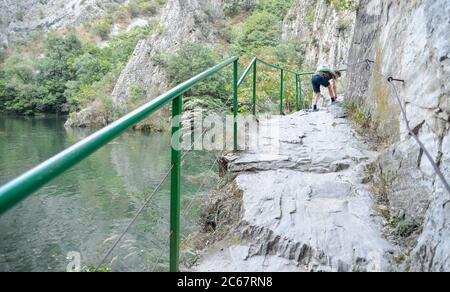 Am Matka Canyon, in der Nähe von Skopje, bindet ein Wanderer seine Schuhbahn.Besucher können den Weg neben dem Fluss Treska und dem ruhigen Wasser des Matka Sees laufen. Stockfoto