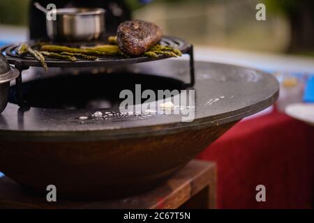 Der Koch grillt Rindersteak und Spargel auf dem Grill im Garten Stockfoto