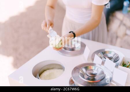 Eisverkäufer legt das Eis in die Tasse. Stockfoto