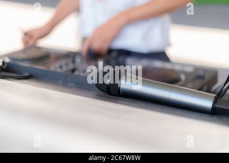 Nahaufnahme eines Mikrofons neben DJ, der bei einem Outdoor-Event Musik spielt. MIC neben Deejay Mischen auf der Party Stockfoto