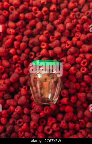 Leere Glas für Himbeer Kochen, auf der Textur von roten reifen Himbeere im Hintergrund. Stockfoto