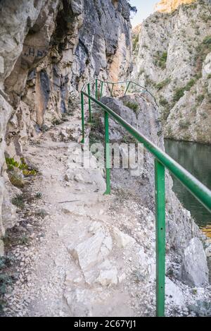 Besucher können den Weg neben dem Fluss Treska entlang der steilen felsigen Berghänge und ruhigen Gewässern des Matka-Sees zu Fuß. Stockfoto