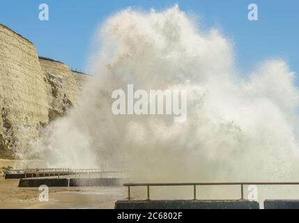 Ganz in der Nähe der aufragenden weißen, schaumigen Wellen, die auf den Fußweg am Meer neben den weißen Klippen bei Rottingdean England stürzen Stockfoto