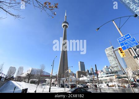 Der CN Turm von Lower Simcoe Street an einem klaren Wintermorgen. Das Metro Convention Center, Ripley's Aquarium und die Straßenschilder sind sichtbar. Stockfoto