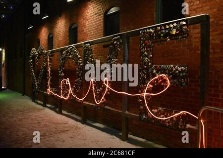 Liebe in Vorhängeschlössern und einem Neonlicht über der Oberseite geschrieben. Liebe Schild in der Nacht im Winter in der historischen Brennerei District in Toronto. Stockfoto