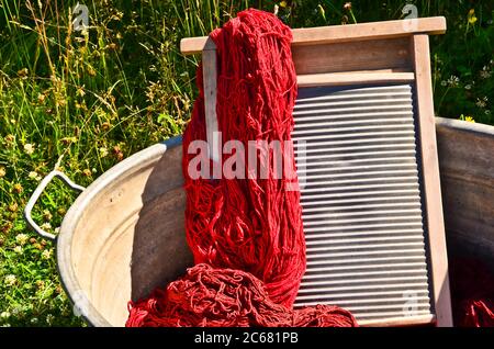 Ein altmodischer Waschtrougt gefüllt mit gefärbten und gewaschenen Schnüren und Seilen aus roter Wolle Stockfoto