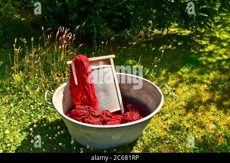 Ein altmodischer Waschtrougt gefüllt mit gefärbten und gewaschenen Schnüren und Seilen aus roter Wolle Stockfoto