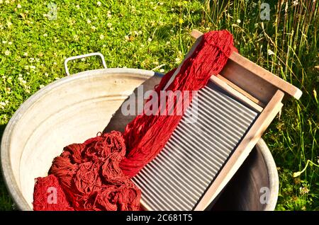 Ein altmodischer Waschtrougt gefüllt mit gefärbten und gewaschenen Schnüren und Seilen aus roter Wolle Stockfoto