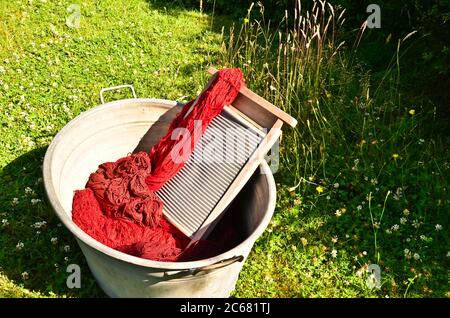 Ein altmodischer Waschtrougt gefüllt mit gefärbten und gewaschenen Schnüren und Seilen aus roter Wolle Stockfoto