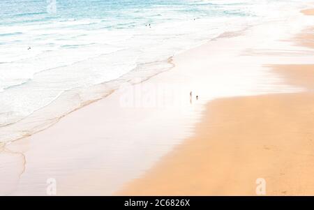 Ein einsame Mann geht mit einem Hund am Strand - Perranporth, Cornwall, Großbritannien Stockfoto