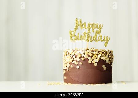 Schokoladen-Geburtstagskuchen mit goldenem 'Happy Birthday'-Schild Stockfoto