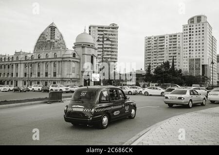 Baku, Aserbaidschan - 2. Mai 2019: Schwarz-weiß-Bild von Autos, die schnell auf der zentralen Zufahrt von Baku fahren, mit typischer azerischer Architektur im Hintergrund Stockfoto