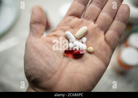 Männliche Hand hält eine Vielzahl von Vitaminen und verschreibungspflichtigen Pillen Stockfoto