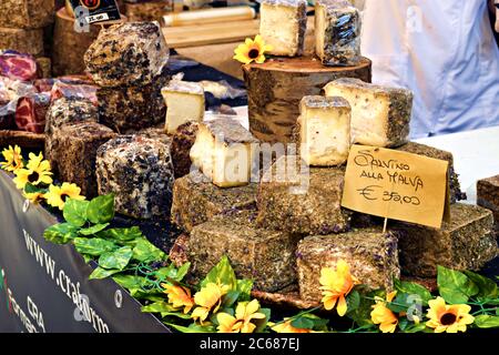 Nahaufnahme von verschiedenen typischen italienischen Käsesorten zum Verkauf an einer Lebensmitteltheke in den Straßen des mittelalterlichen Dorfes Asciano in der Toskana, Italien Stockfoto