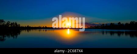 Blick auf See reflektierende Sonne und Wald bei Sonnenuntergang im Everglades National Park, Florida, USA Stockfoto