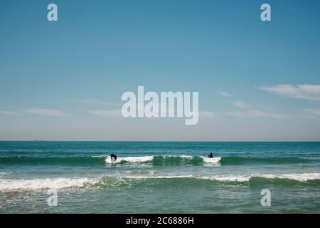 Surfer paddeln aus, um eine Welle vor der Küste von Südkorea zu fangen Stockfoto