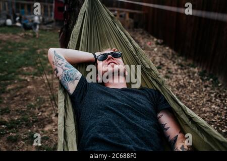 Glücklicher Mann, der sich in der Hängematte entspannt Stockfoto