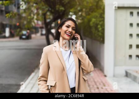 Schöne hispanische Frau, die auf der Straße telefoniert Stockfoto