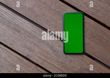Draufsicht auf Green Screen Smartphone auf Retro Holztisch Stockfoto