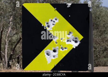 Rotes Straßenverkehrsschild voller Einschusslöcher. Nahaufnahme. Stockfoto