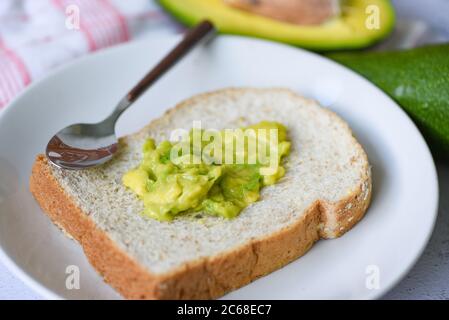 Avocado Dip püriert / Avocado Toast auf weißem Teller Hintergrund Früchte gesunde Ernährung Konzept Stockfoto