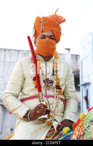 Jodhpur, Rajashtbn, Indien. 30. Juni 2020: Indischer Bräutigam trägt Maske auf Pferd sitzend, Menschen heiraten nach Leichtigkeit in Sperre während COVID-19 pa Stockfoto