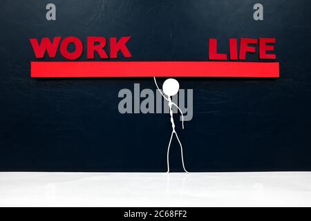 Work-Life-Balance-Konzept. Menschliche Stockfigur balanciert eine rote Wippe mit Arbeit und Leben Wort Ausschnitt. Stockfoto
