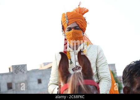 Jodhpur, Rajashtbn, Indien. 30. Juni 2020: Indischer Bräutigam trägt Maske auf Pferd sitzend, Menschen heiraten nach Leichtigkeit in Sperre während COVID-19 pa Stockfoto