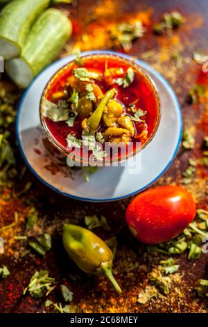 Nahaufnahme von frischem indischem Mittagsgericht Luffa oder Galka nu Shaak in einem Glasbehälter mit allen Zutaten auf einer rostfarbenen Oberfläche. Stockfoto