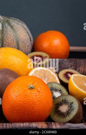 Gehackte grüne und goldene Kiwis, orangefarbene Hälften, Honigmelonen und chinesische Laternen Früchte. Stockfoto