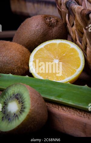 Kiwi und saure Zitronenhälften und ein Aloe Vera Blatt in einem Holzkorb. Stockfoto