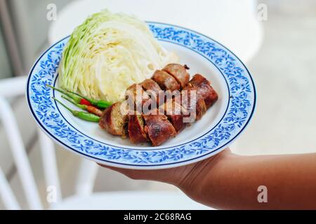 Sai Au (Northern Thai Spicy Sausage) serviert auf dem Teller mit chinesischem Kohl und Chili Stockfoto