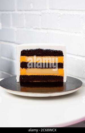 Scheibe Kuchen mit Schokoladenschwamm Schichten und orange Füllung auf weißem Hintergrund. Stockfoto