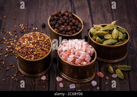 Meersalz, Sesam und schwarze Pfefferbohnen in winzigen Kupfertöpfen. Stockfoto