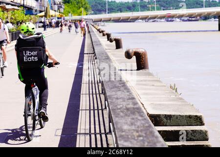 Bordeaux , Aquitanien / Frankreich - 07 06 2020 : uber isst Biker-Lieferer mit großem Rucksack auf dem Fahrrad auf dem Kai Stockfoto