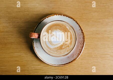 Kaffee mit Milch in einer Tasse. Cappuccino. Auf hellbraunem Hintergrund. Draufsicht. Stockfoto