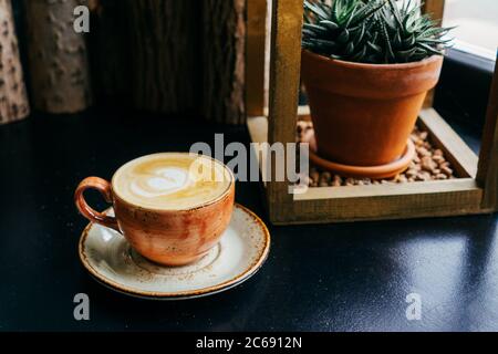 Kaffee mit Milch in einer Tasse. Cappuccino. Auf schwarzem Holz Hintergrund. Saftig im Hintergrund. Stockfoto