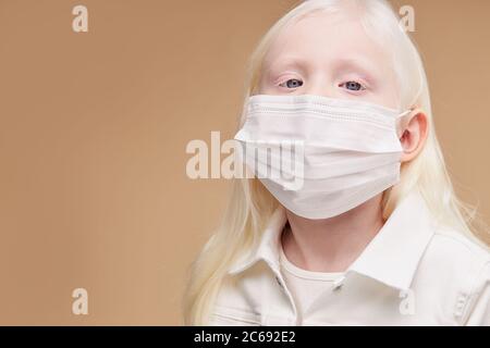 Nahaufnahme Porträt von kranken kaukasischen Kind in Maske, schützen Sie sich vor Unbeschwerlichkeit, Coronavirus, covid-19. albino Mädchen hat ungewöhnlich charmante Erscheinung. sh Stockfoto