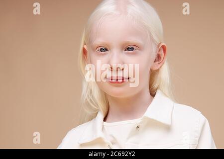 Portrait von lächelnd Albino Kind Mädchen isoliert über beige Hintergrund, ungewöhnliche interessante Erscheinung des Mädchens ist hypnotisierend, natürliche Schönheit Konzept Stockfoto