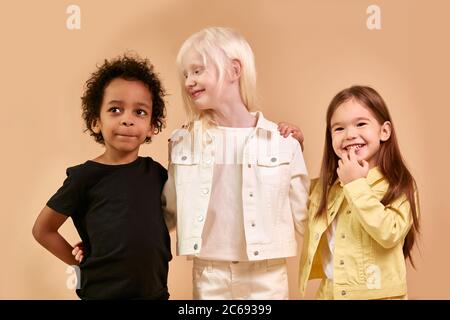 Glücklich lächelnde Kinder isoliert im Studio, Albino, afrikanische und amerikanische Kinder lachen, Lächeln auf Kamera, tragen helle Kleidung. Kinder Vielfalt, kindn Stockfoto