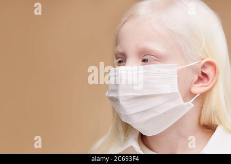 Nahaufnahme Porträt von kranken kaukasischen Kind in Maske, schützen Sie sich vor Unmut, Coronavirus, covid-19. albino Mädchen hat ungewöhnliche charmante Erscheinung, ist Stockfoto