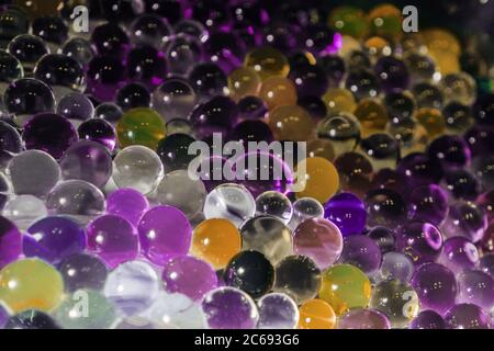 Abstrakte Textur, Farbkugeln aus Hydrogel für den Hintergrund. Hydrogelperlen. Violette und orange Farben, Stockfoto