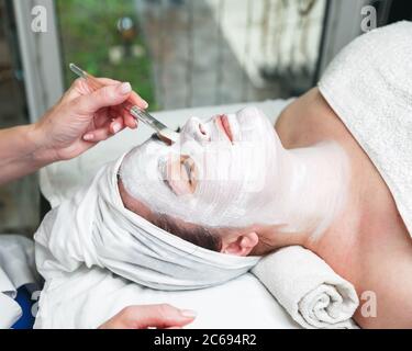 Kosmetikerin, die Gesichtsmaske auf das Gesicht der Frau mit Stock Stockfoto